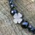 Zbliżenie na koniczynę z naturalnego hematytu 7x7mm w bransoletce NOIR CLOVER